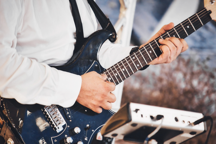 lose-up of a professional man's hands playing the fretboard of an electric blues guitar